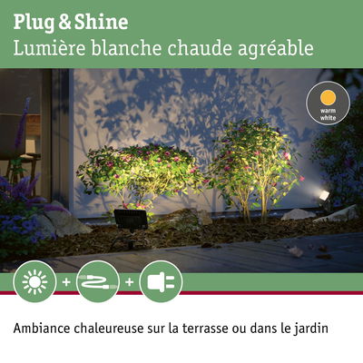 Éclairage LED Plug & Shine blanc chaud illuminant des buissons verts et une terrasse pour une ambiance extérieure chaleureuse
