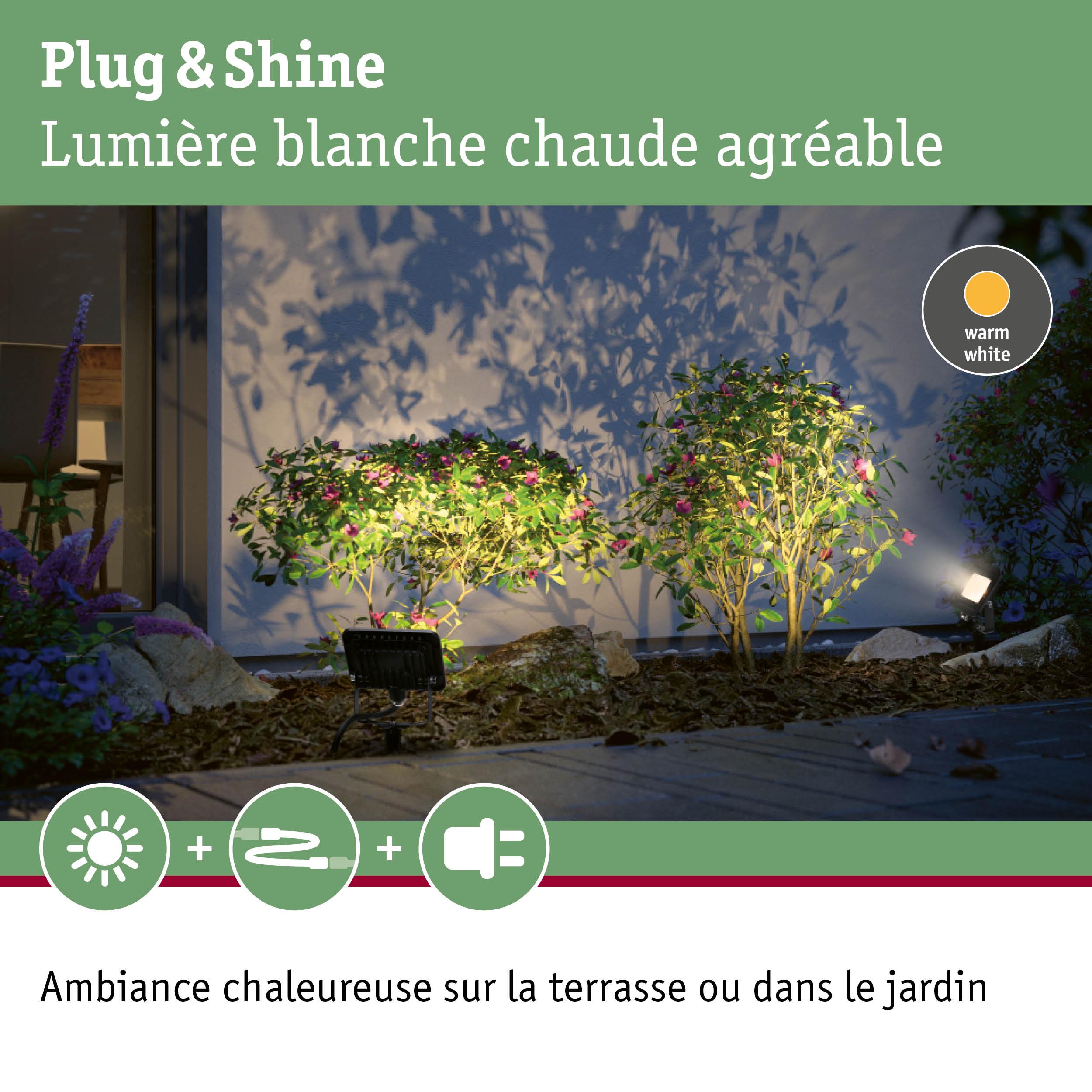 Éclairage LED Plug & Shine blanc chaud illuminant des buissons verts et une terrasse pour une ambiance extérieure chaleureuse
