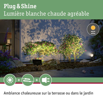 Éclairage LED Plug & Shine blanc chaud illuminant des buissons verts et une terrasse pour une ambiance extérieure chaleureuse