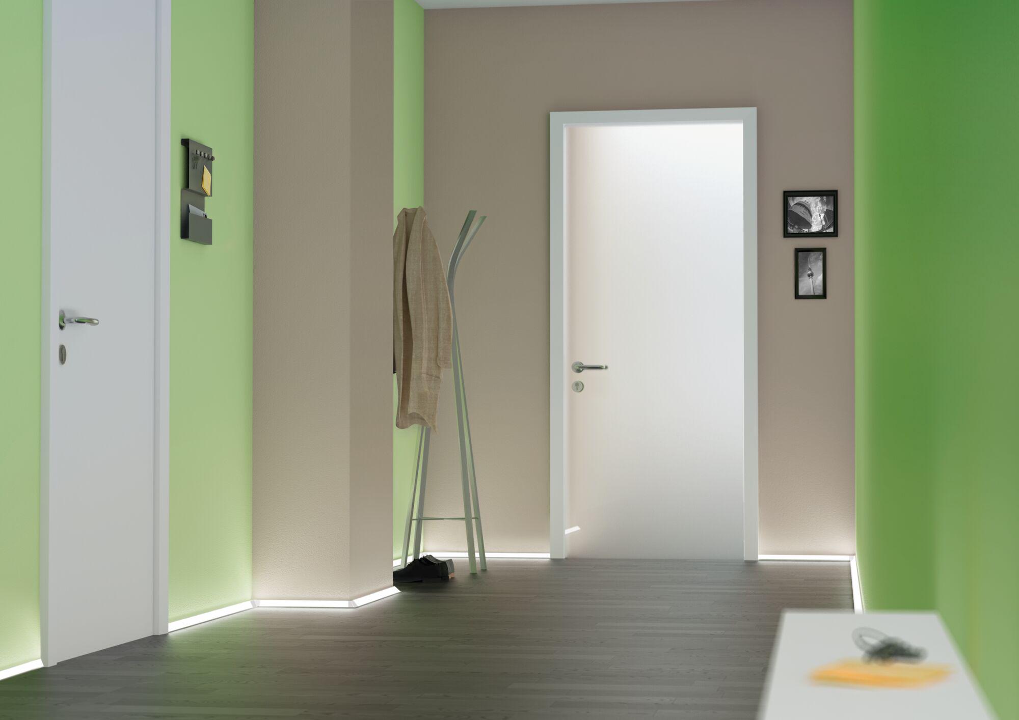Modern hallway with white doors, green walls, and LED floor lighting for stylish interior design