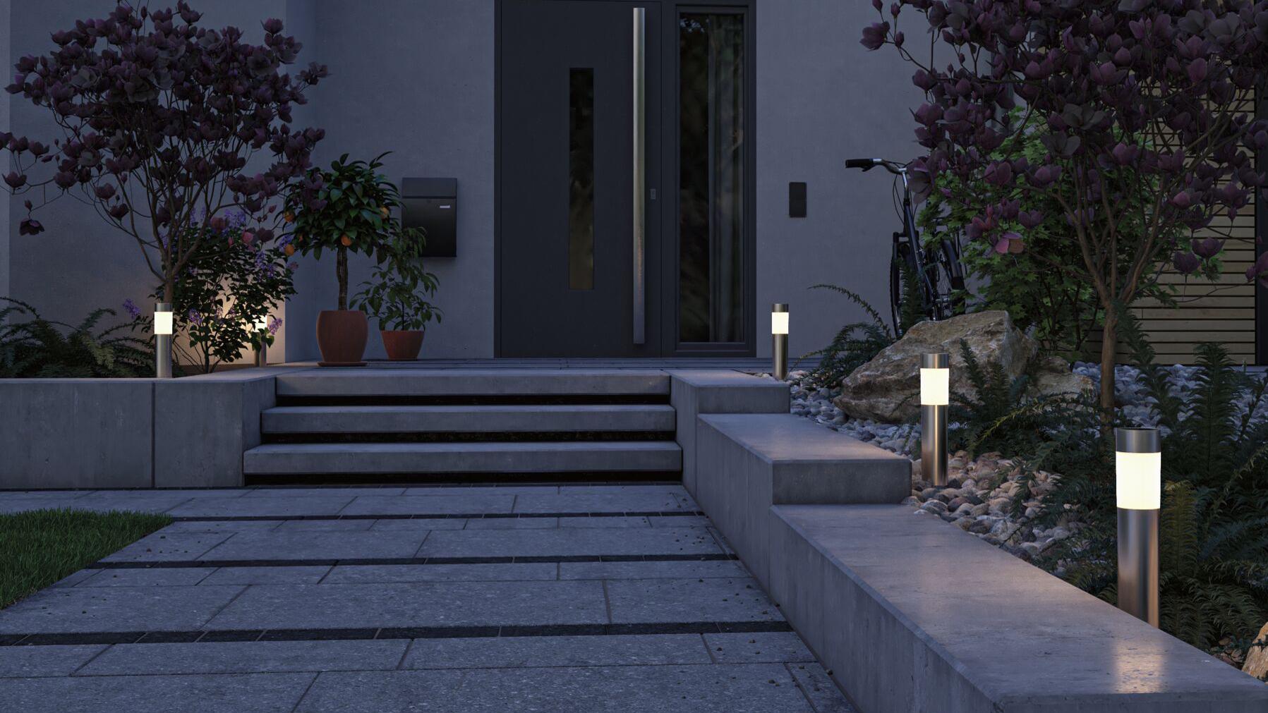 Moderne Solarleuchten aus Edelstahl mit warmweißem Licht beleuchten den Hauseingang und Gartenweg bei Nacht.