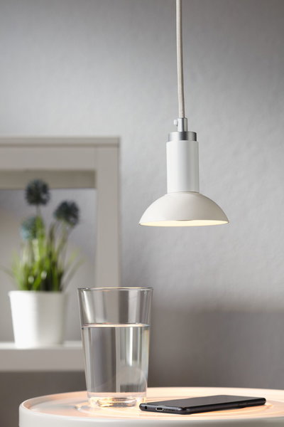 Suspension blanche en métal avec câble en tissu au-dessus d’un verre d’eau et smartphone sur table, éclairage LED moderne