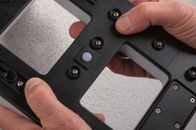 Boîtier en plastique noir avec vis et interrupteur marche/arrêt tenu par des mains, gros plan.