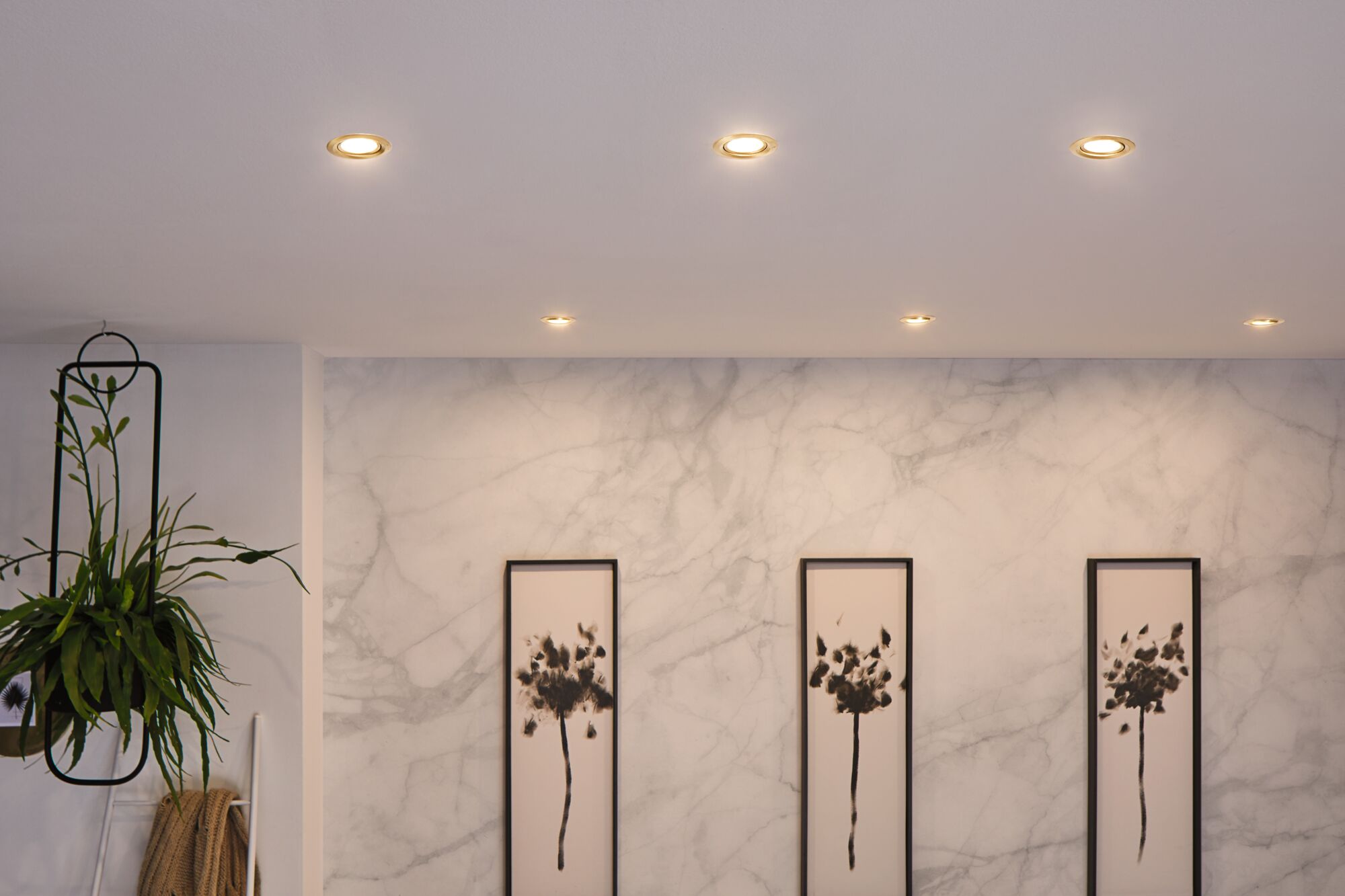 Six spots LED encastrés blanc chaud éclairent un mur en marbre moderne avec des œuvres d'art minimalistes.