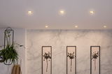 Six recessed LED ceiling lights in warm white illuminate a modern marble wall with minimalist artwork.