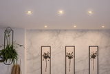 Zes ingebouwde LED-plafondlampen met warm wit licht in moderne woonkamer met planten en kunst.