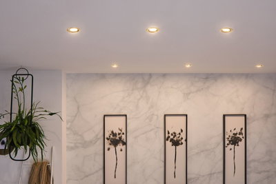 Zes ingebouwde LED-plafondlampen met warm wit licht in moderne woonkamer met planten en kunst.