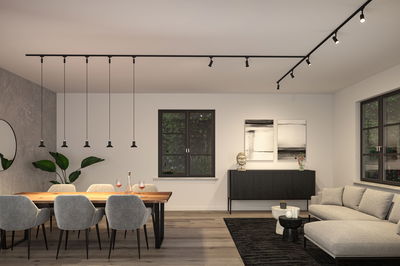Modern dining and living area with black track and pendant lights, grey chairs, and wooden table