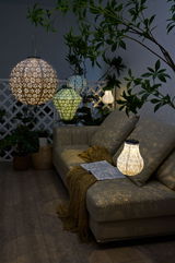 Meer kleurige decoratieve hanglampen met patroon van metaal en kunststof verlichten gezellige zithoek met bank.