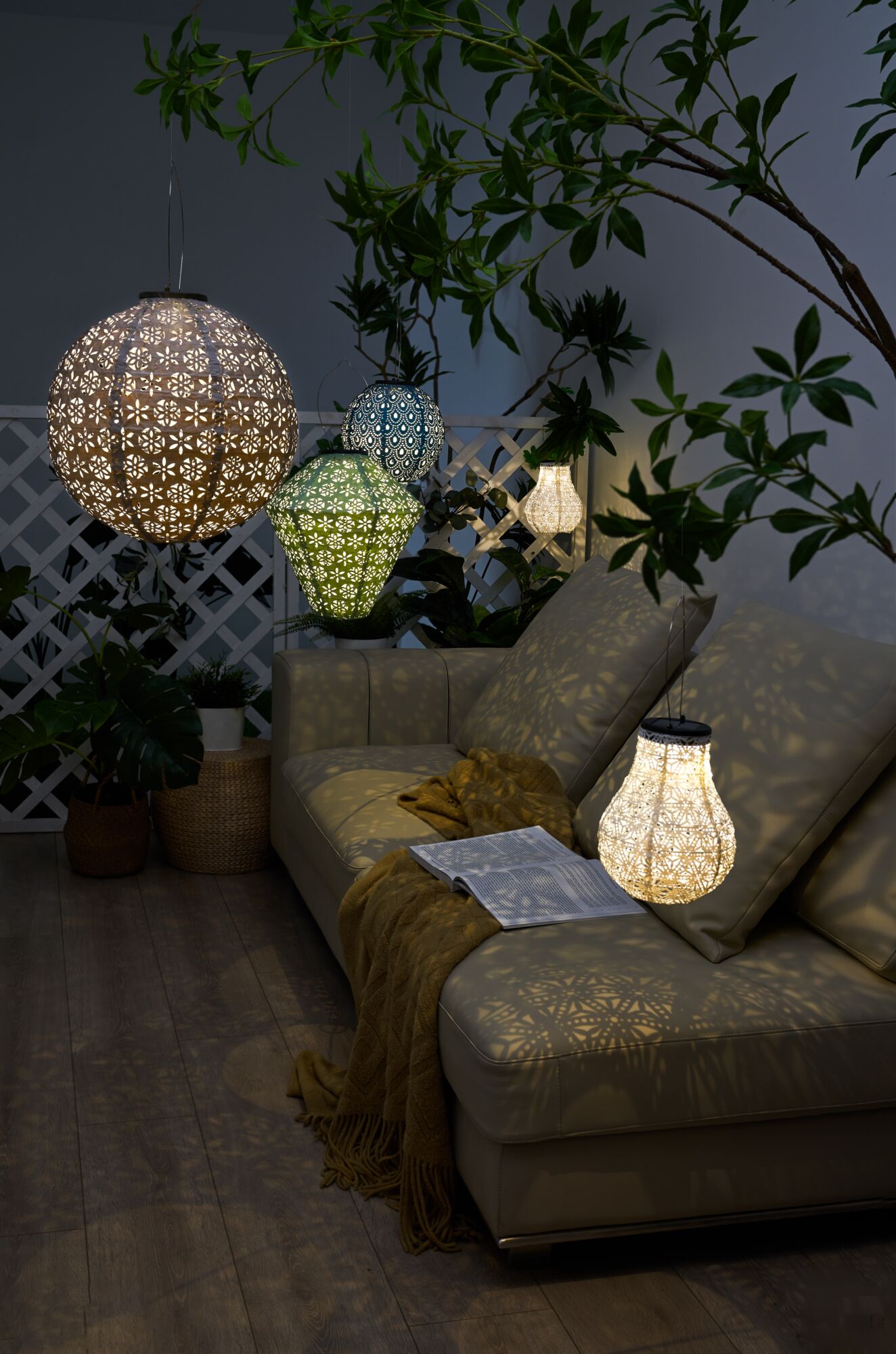 Multicolored decorative hanging lamps with patterned metal and plastic illuminate cozy seating area with sofa.