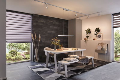 Modern dining room with white table, bench, gray rug, and minimalist LED ceiling light fixture