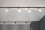 Moderne zwarte rails met vier witte glazen lampenkappen voor sfeerverlichting in woonruimtes.