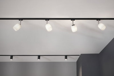 Moderne schwarze Schienensystem-Deckenleuchte mit vier weißen Glaslampenschirmen für Wohnräume.