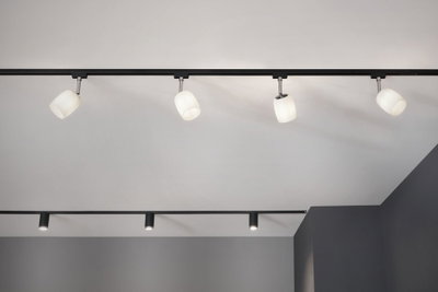 Moderne schwarze Schienensystem-Deckenleuchte mit vier weißen Glaslampenschirmen für Wohnräume.