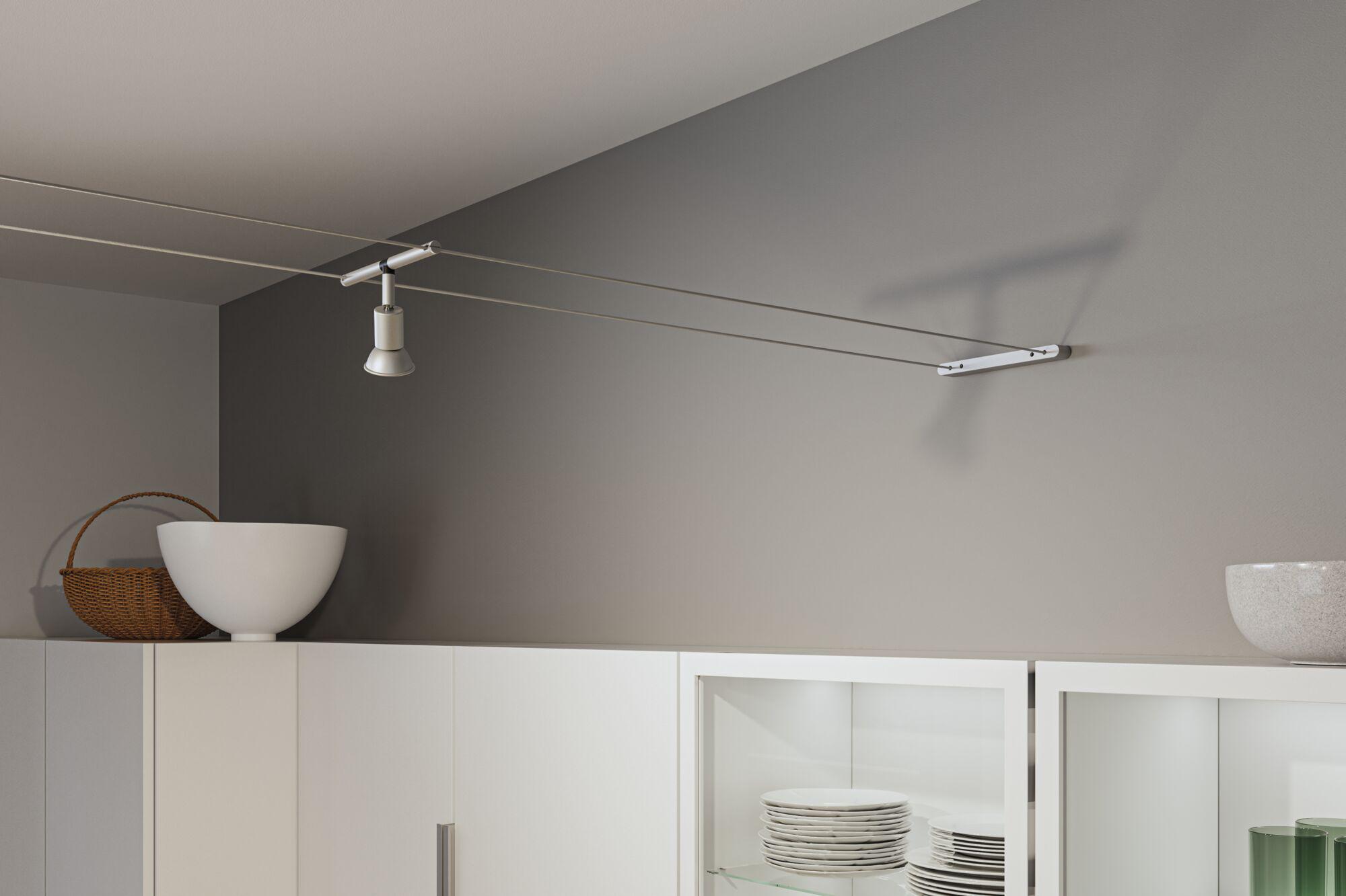 Moderner weißer Seilstrahler aus Metall an grauer Wand über weißem Küchenschrank mit Geschirr.