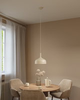 Beige metal pendant light above round wooden table with beige chairs and ceramic tableware in dining room
