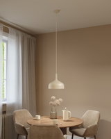 Beige metalen hanglamp boven ronde houten tafel met beige stoelen en keramisch servies in eetkamer