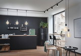 Cuisine moderne avec suspensions noires et plan de travail en bois, spots LED élégants au plafond.