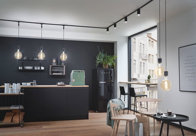 Moderne Küche mit schwarzen Hängelampen und Holzarbeitsplatte, stilvolle LED-Deckenstrahler.