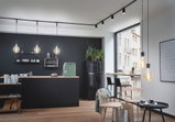 Moderne Küche mit schwarzen Hängelampen und Holzarbeitsplatte, stilvolle LED-Deckenstrahler.