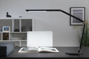 Schwarze LED-Schreibtischlampe mit verstellbarem Arm auf dunklem Tisch mit offenem Buch, moderne Bürobeleuchtung