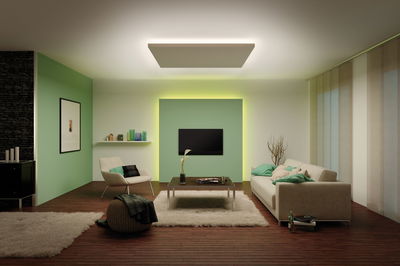 Modern living room with green accent wall panel and indirect LED lighting for ambient mood lighting
