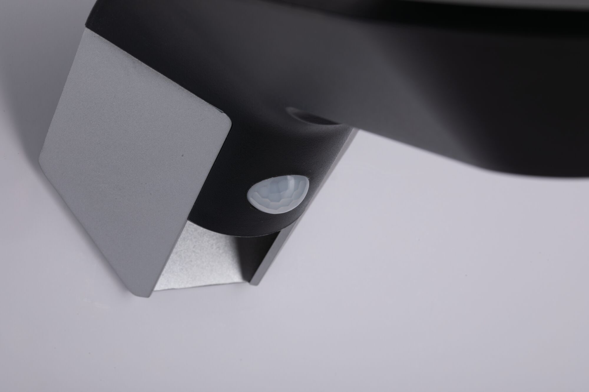 Gros plan sur capteur noir avec support métallique argenté pour systèmes d'éclairage intelligents