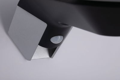 Close-up of black sensor with silver metal bracket for smart lighting systems and motion detection