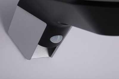 Close-up of black sensor with silver metal bracket for smart lighting systems and motion detection