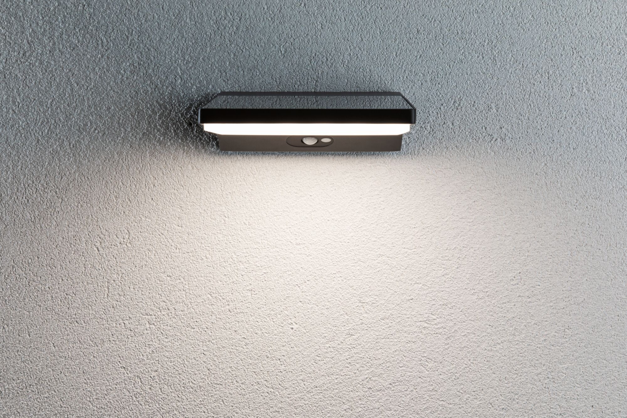 Zwarte metalen LED-wandlamp met bewegingssensor op grijze muur voor buitenverlichting