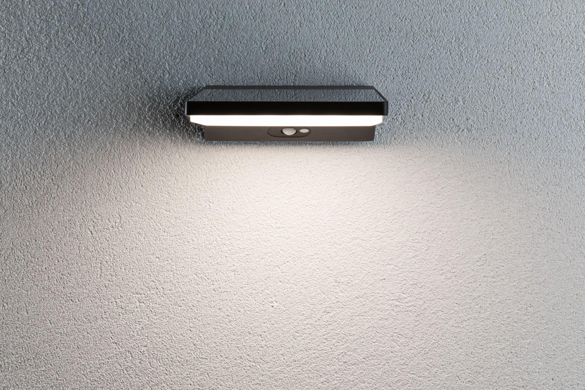 Black LED wall light with motion sensor on grey wall, energy-saving outdoor lighting