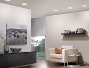 Moderner Wohnraum mit weißem Ledersessel, schwarzem Sideboard und runden Deckenleuchten in Weiß.
