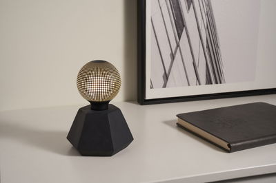 Moderne tafellamp met zwarte zeshoekige voet en verlichte bol met stippenpatroon voor sfeerverlichting.