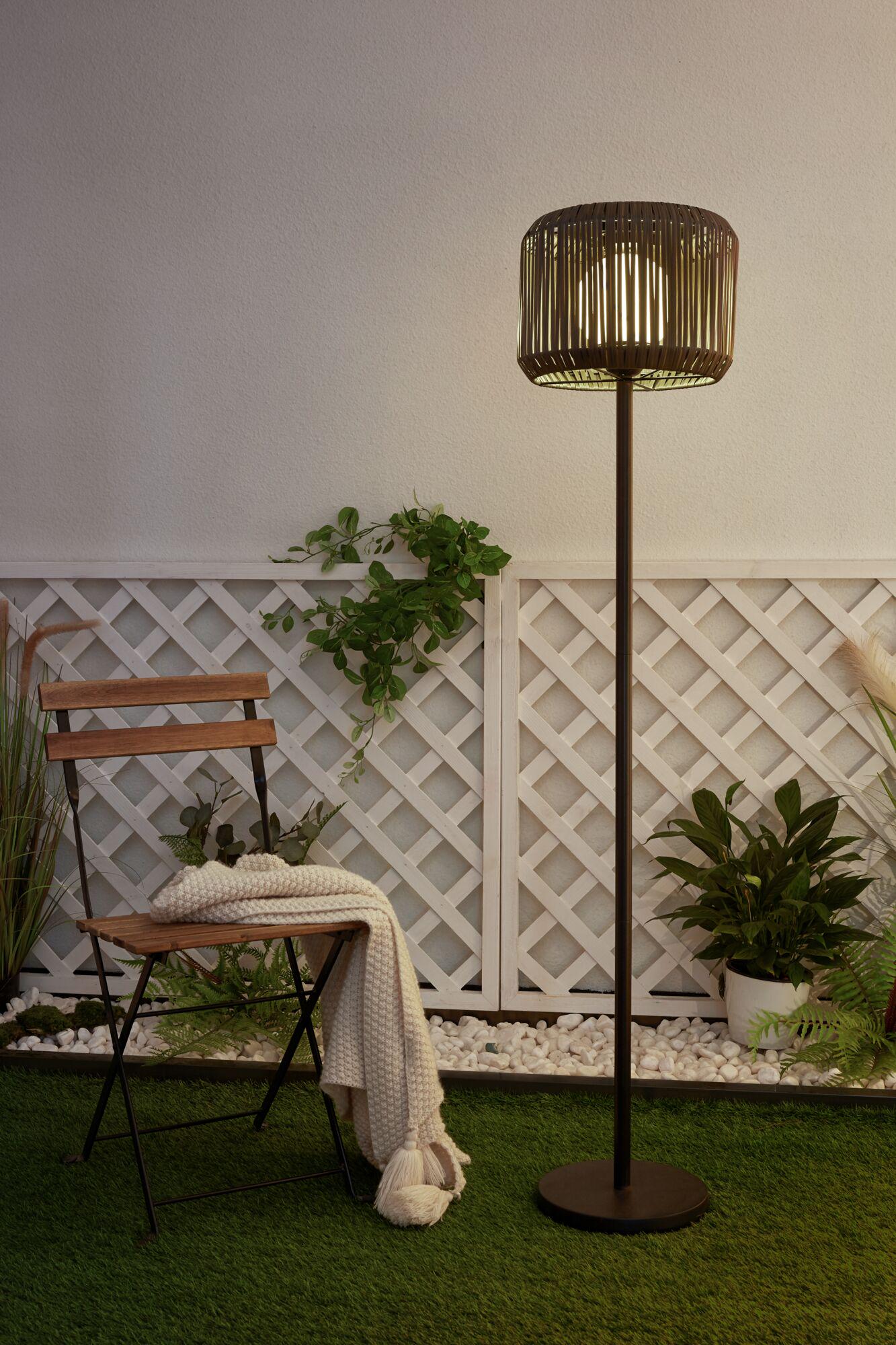 Outdoor floor lamp with brown metal frame and wooden slat lampshade in garden setting