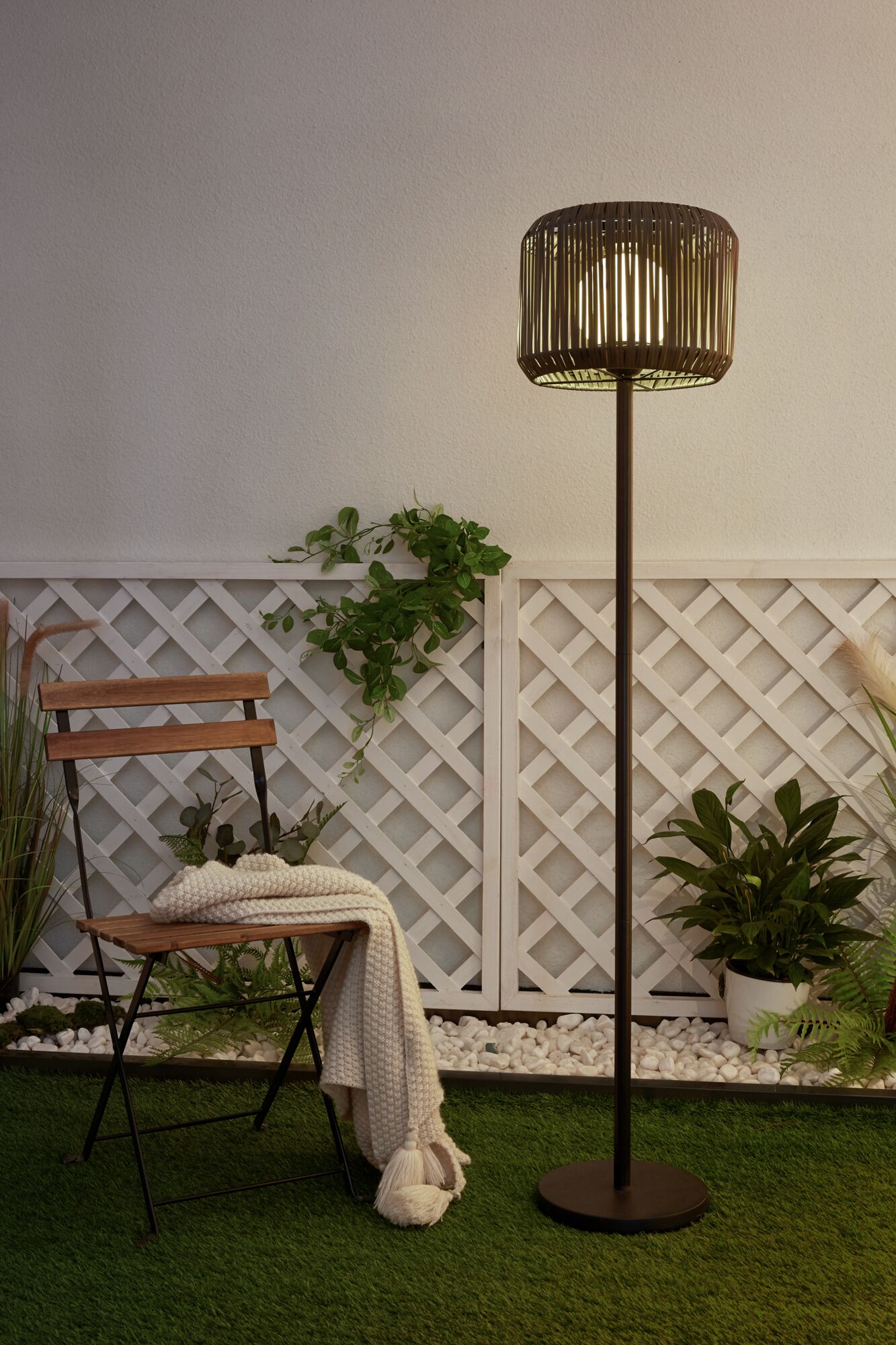 Outdoor floor lamp with brown metal frame and wooden slat lampshade in garden setting