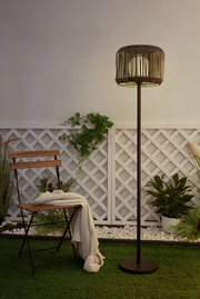 Outdoor floor lamp with brown metal frame and wooden slat lampshade in garden setting