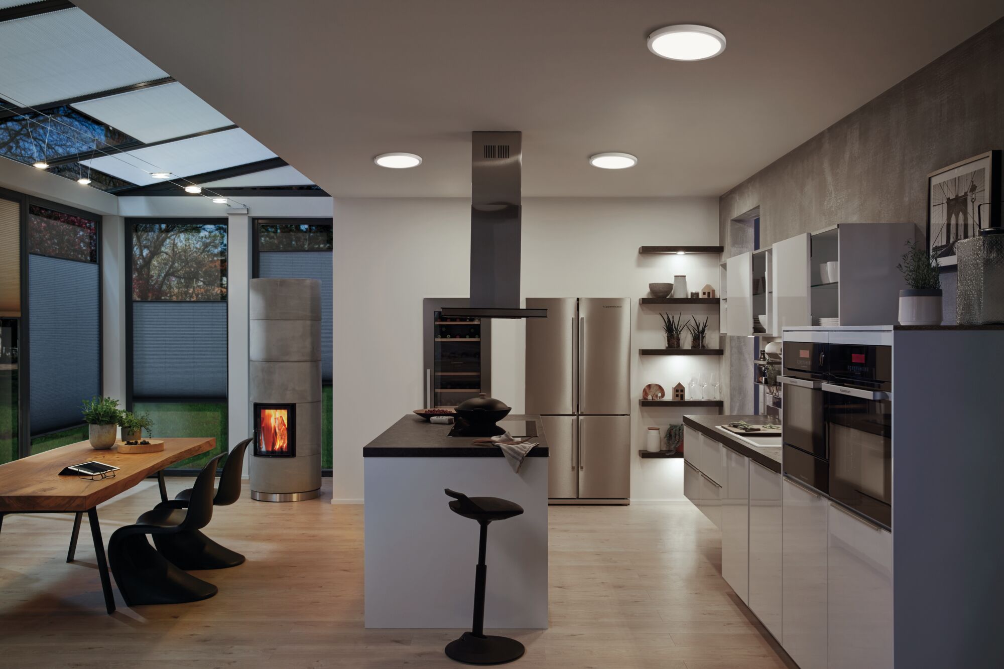 Modern kitchen with white gloss cabinets, black countertop and round ceiling lights emitting warm white light