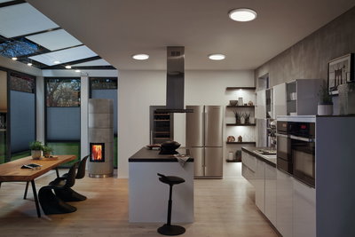 Modern kitchen with white gloss cabinets, black countertop and round ceiling lights emitting warm white light