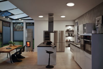 Modern kitchen with stainless steel appliances, wooden dining table, and round ceiling LED lights in warm white