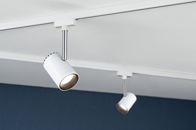 Two white metal LED spotlights on track system mounted on white ceiling for modern lighting