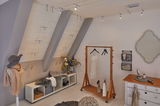 Modern dressing room with wooden clothes rack, white sideboard, and adjustable silver ceiling spotlights.