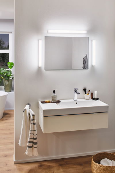 Salle de bain moderne avec lavabo mural blanc, miroir et appliques LED pour un éclairage lumineux