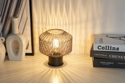 Table lamp with smoked glass and black metal base casting decorative light patterns on surfaces.