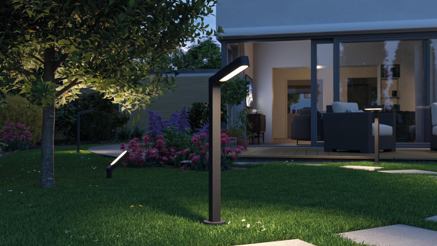 Lanterne extérieure LED noire en métal éclairant un chemin de jardin près de la terrasse