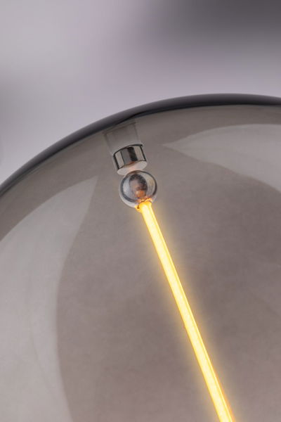 Gros plan sur une tige lumineuse LED blanc chaud dans une lampe en verre gris pour éclairage intérieur moderne