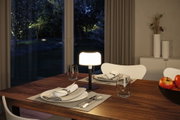 Lampe de table moderne avec abat-jour blanc et pied noir sur table en bois foncé dans salle à manger.