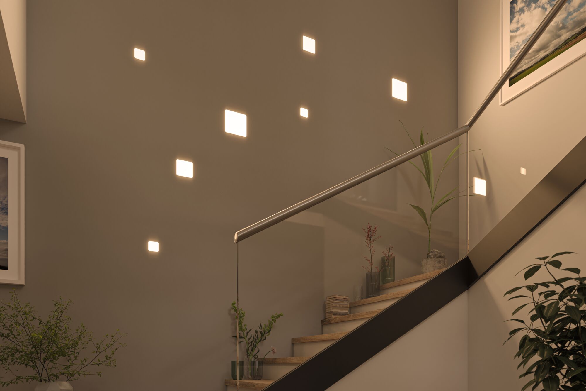 Moderne vierkante LED-wandlampen in warm wit aan trapmuur met glazen leuning en planten.