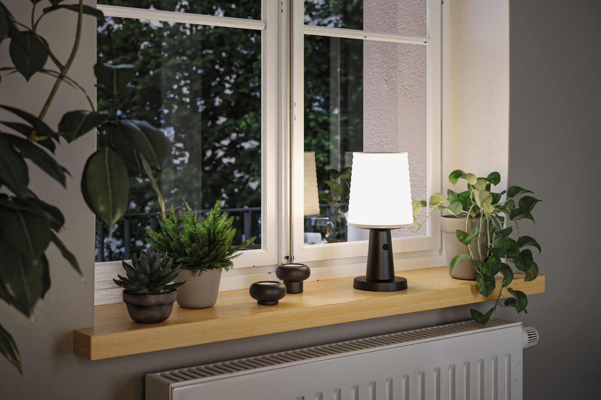 Moderne schwarze Tischlampe mit weißem Lampenschirm auf Holzfensterbank neben grünen Zimmerpflanzen.