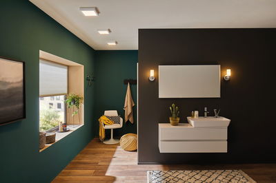 Salle de bain moderne avec lavabo blanc, miroir, appliques murales blanc chaud et sol en bois.