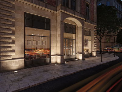 Außenansicht eines Restaurants mit warmweißer LED-Bodenbeleuchtung an Sandsteinfassade und Gehweg.